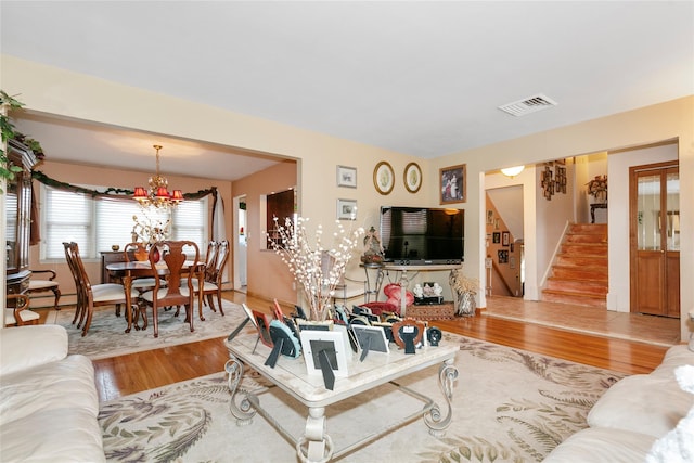 living area featuring wood finished floors, visible vents, a notable chandelier, and stairs