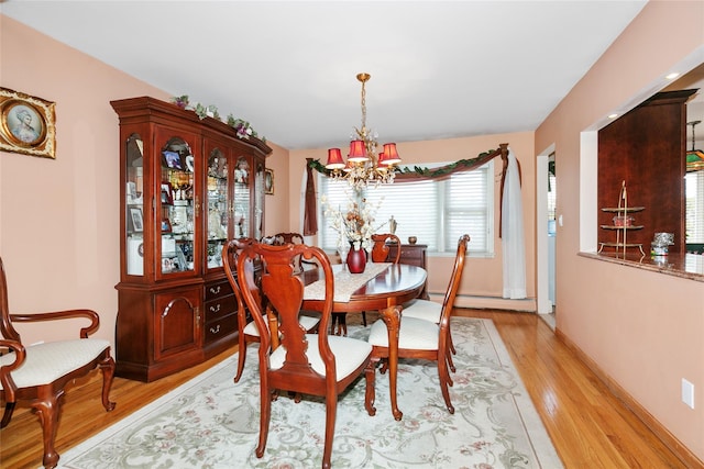 dining area with light wood-style flooring, baseboards, baseboard heating, and a notable chandelier