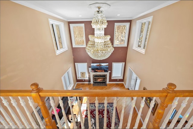 staircase with wood-type flooring, ornamental molding, and a chandelier