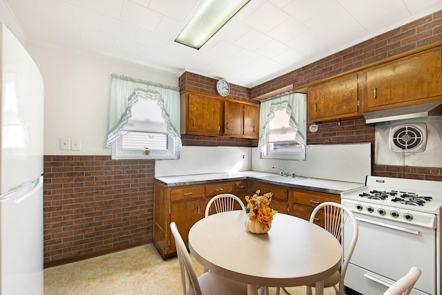 kitchen with brick wall, sink, and white appliances