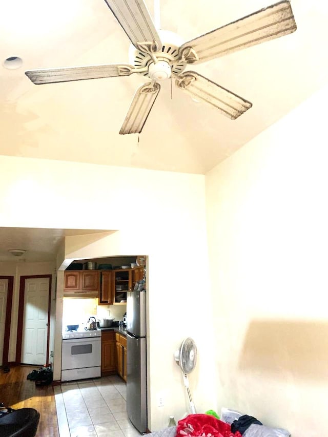 kitchen with ceiling fan, light tile patterned flooring, stainless steel refrigerator, and white stove