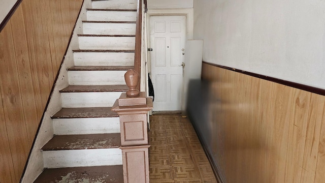 staircase featuring parquet floors and wood walls