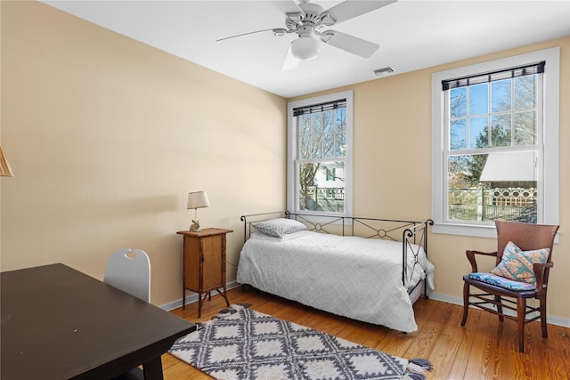 bedroom with multiple windows, wood-type flooring, and ceiling fan