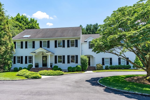 colonial home with curved driveway and a front yard