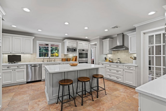 kitchen with wall chimney exhaust hood, light countertops, white cabinetry, and stainless steel appliances