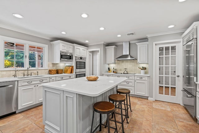 kitchen with a center island, white cabinets, a sink, wall chimney range hood, and built in appliances