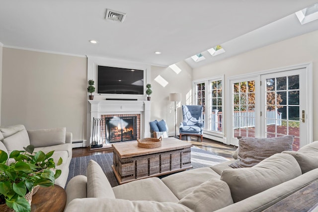 living area with baseboard heating, a skylight, a fireplace, and visible vents