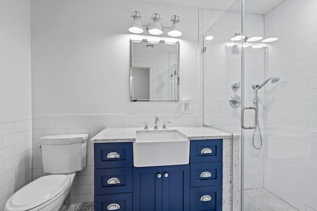 bathroom with toilet, a shower stall, tile walls, and vanity