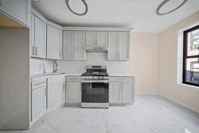 kitchen with stainless steel gas range oven, marble finish floor, light countertops, under cabinet range hood, and a sink