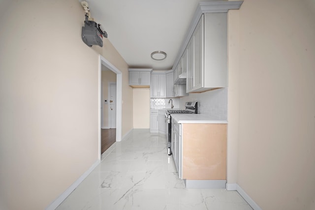 kitchen with stainless steel gas range oven, baseboards, marble finish floor, light countertops, and decorative backsplash