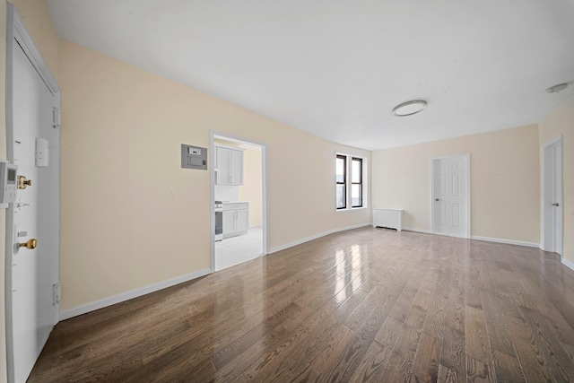 unfurnished room with radiator, baseboards, and wood finished floors