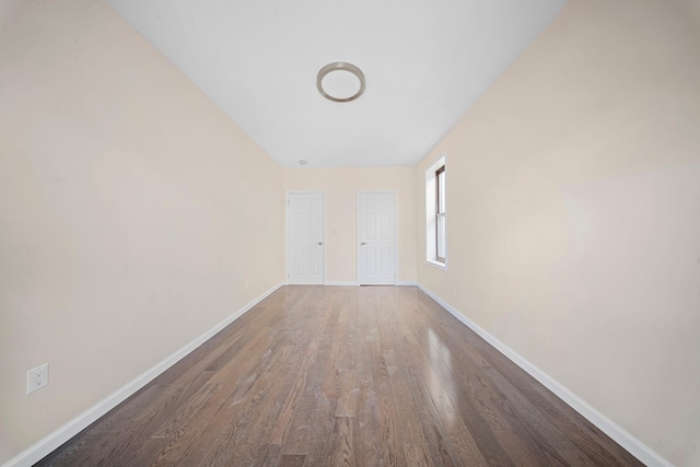 spare room featuring baseboards and dark wood finished floors