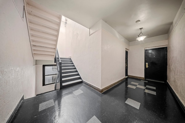 foyer entrance featuring stairs, baseboards, and a textured wall