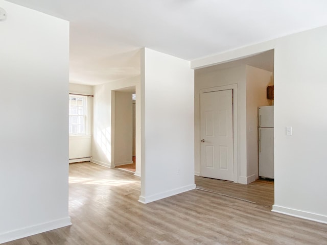 spare room featuring a baseboard radiator and light hardwood / wood-style floors