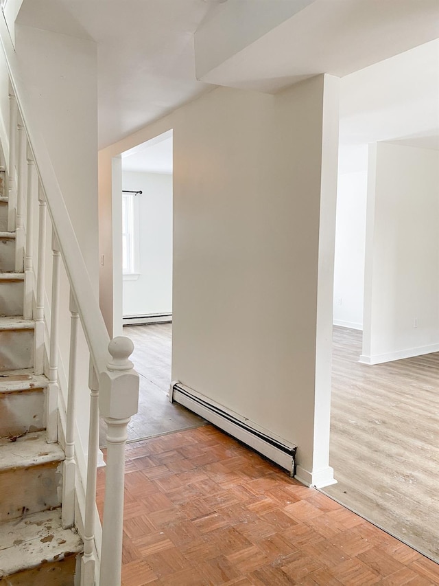 stairs with parquet floors and a baseboard heating unit