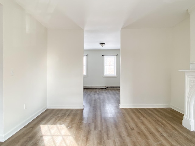 unfurnished living room with baseboard heating, a fireplace, and light wood-type flooring