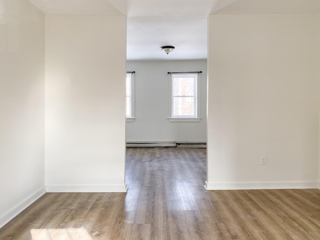 spare room with a baseboard heating unit and light hardwood / wood-style floors