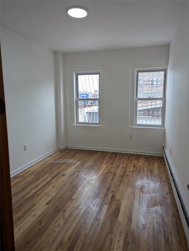 spare room with dark hardwood / wood-style flooring, a wealth of natural light, and baseboard heating