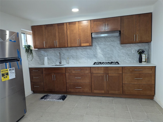 kitchen with tasteful backsplash, gas cooktop, stainless steel fridge, and sink