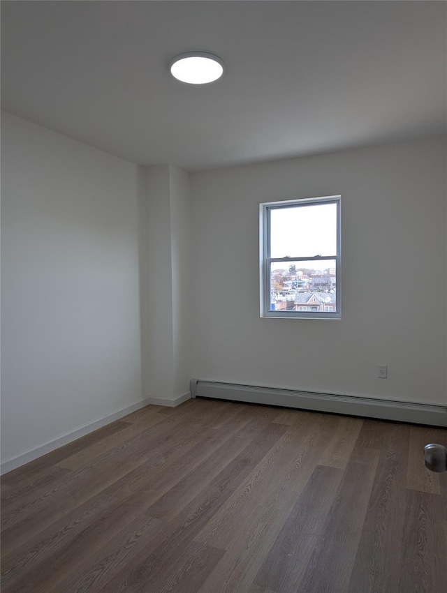 empty room featuring wood-type flooring and baseboard heating