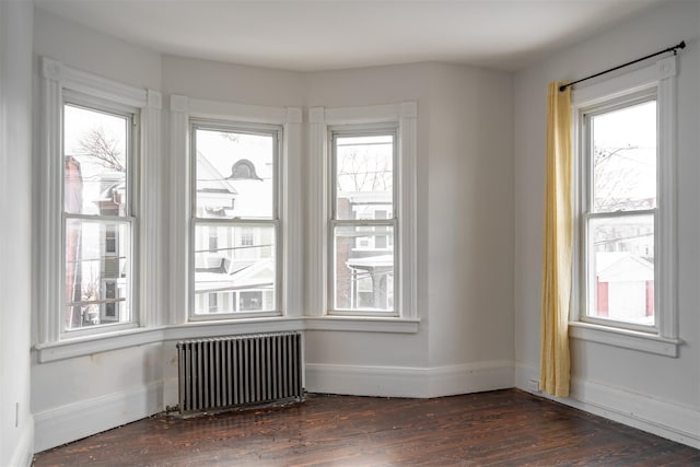 empty room with dark hardwood / wood-style floors and radiator heating unit