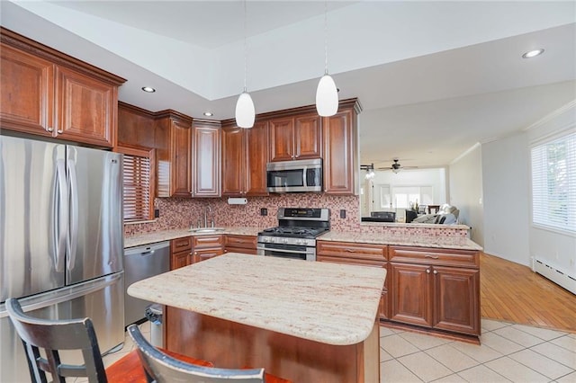 kitchen featuring sink, a center island, hanging light fixtures, appliances with stainless steel finishes, and a kitchen breakfast bar