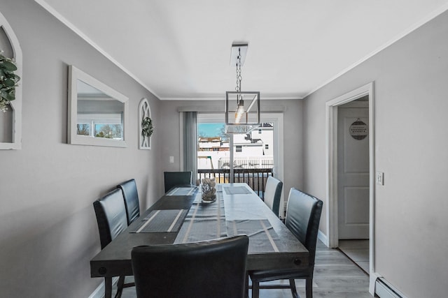 dining area with baseboard heating, ornamental molding, and light wood-type flooring