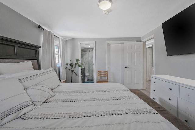 bedroom featuring a closet, ensuite bath, and dark hardwood / wood-style floors