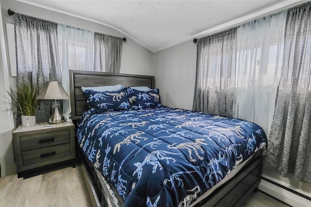 bedroom featuring vaulted ceiling, hardwood / wood-style floors, and a baseboard radiator