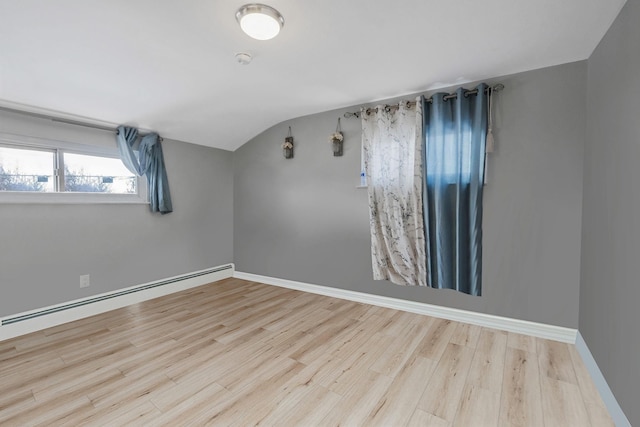 spare room featuring wood-type flooring, lofted ceiling, and a baseboard radiator