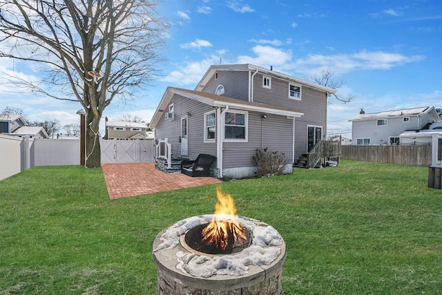 rear view of property featuring a yard, a patio area, and an outdoor fire pit