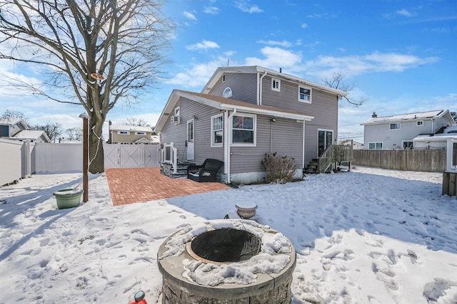 snow covered back of property featuring an outdoor fire pit