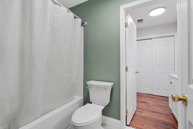 bathroom with hardwood / wood-style flooring, shower / bath combination with curtain, and toilet