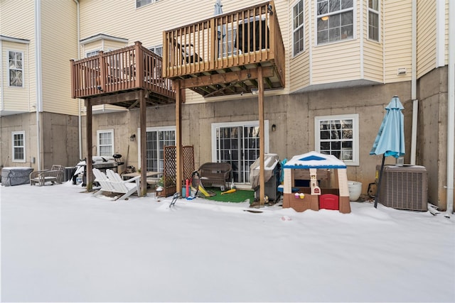 snow covered house featuring central air condition unit and a deck