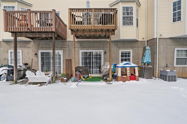 snow covered back of property featuring a wooden deck and central AC