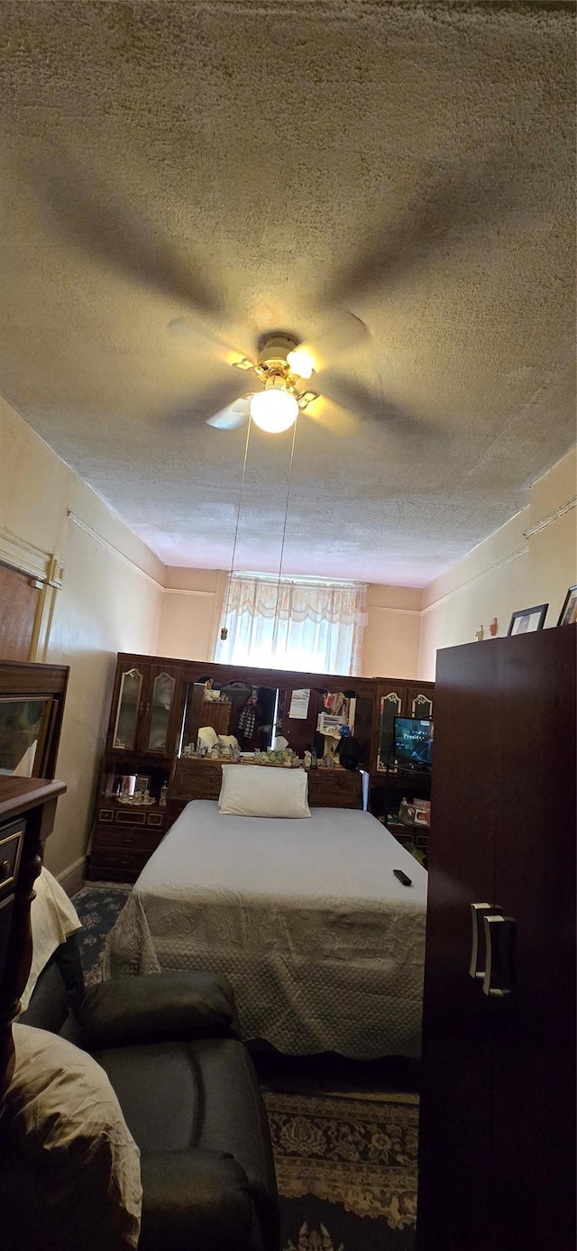 bedroom with ceiling fan and a textured ceiling