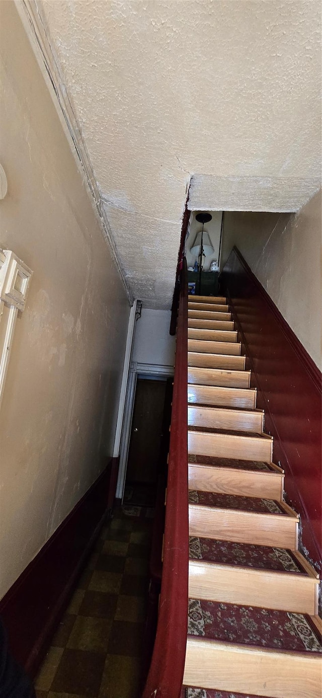 staircase featuring a textured ceiling