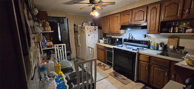 kitchen with sink, ceiling fan, white refrigerator with ice dispenser, range with gas stovetop, and oven