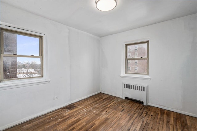 spare room with dark wood-type flooring and radiator heating unit