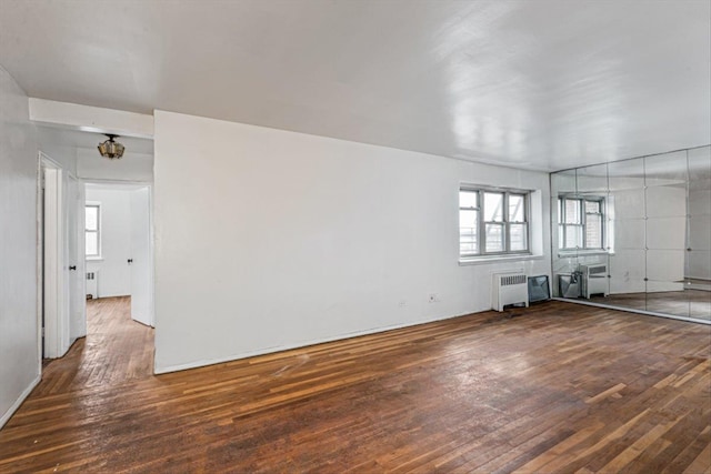 unfurnished living room with a wealth of natural light, radiator, and dark wood-type flooring