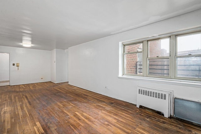 spare room with dark hardwood / wood-style flooring and radiator heating unit