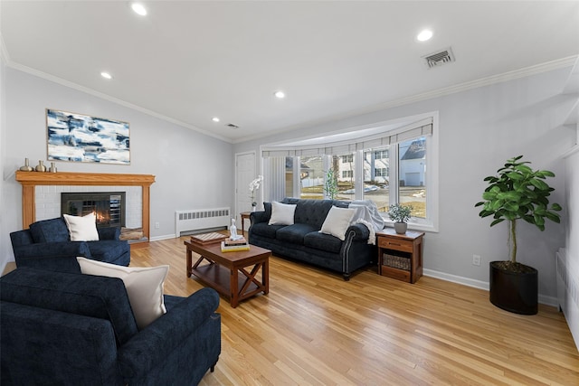 living room with crown molding, vaulted ceiling, a brick fireplace, light hardwood / wood-style flooring, and radiator heating unit