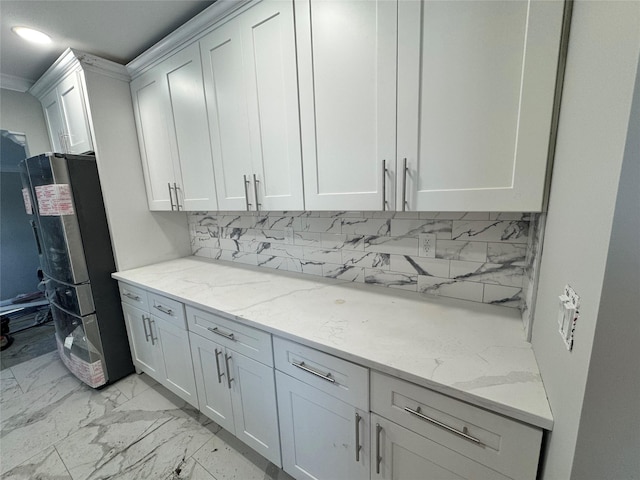 kitchen featuring white cabinetry, stainless steel fridge, and light stone countertops