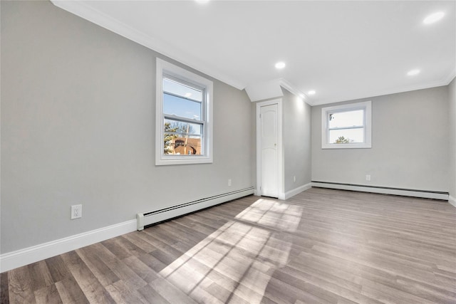 basement with light wood-type flooring, baseboard heating, and ornamental molding