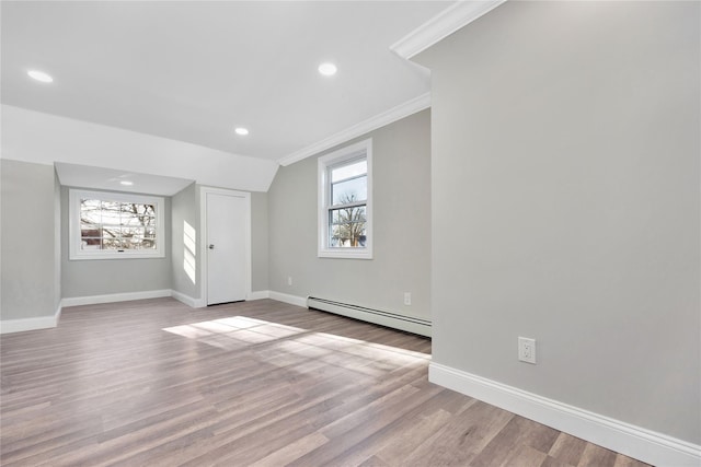 additional living space with light hardwood / wood-style flooring, a baseboard heating unit, and lofted ceiling