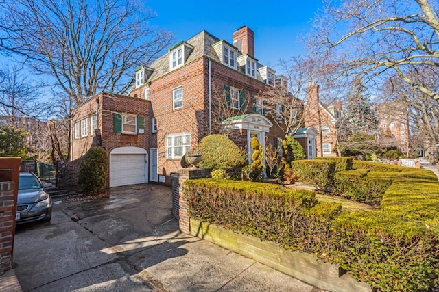 view of front of home with a garage, brick siding, driveway, and mansard roof