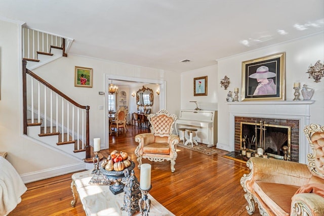 living area featuring baseboards, ornamental molding, wood finished floors, stairs, and a fireplace