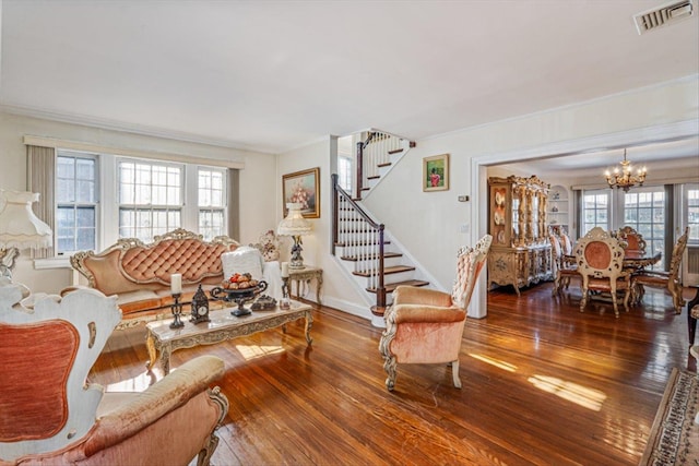 living room with a notable chandelier, visible vents, stairs, ornamental molding, and dark wood finished floors