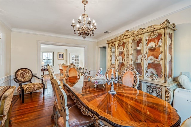 dining space featuring a notable chandelier, visible vents, dark wood-type flooring, and ornamental molding