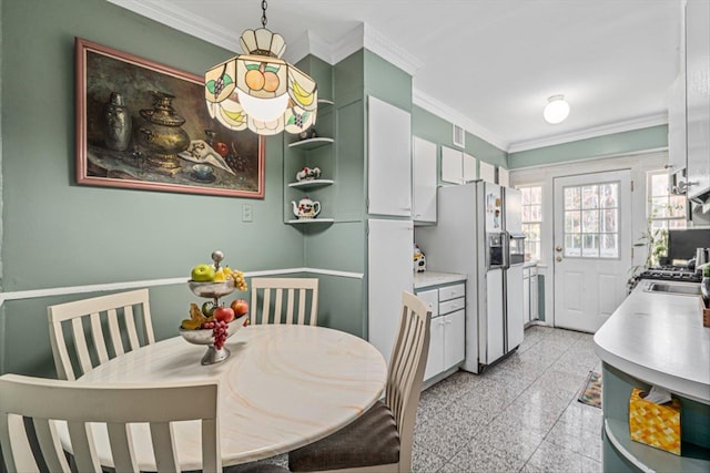 kitchen featuring pendant lighting, crown molding, light countertops, granite finish floor, and white cabinets